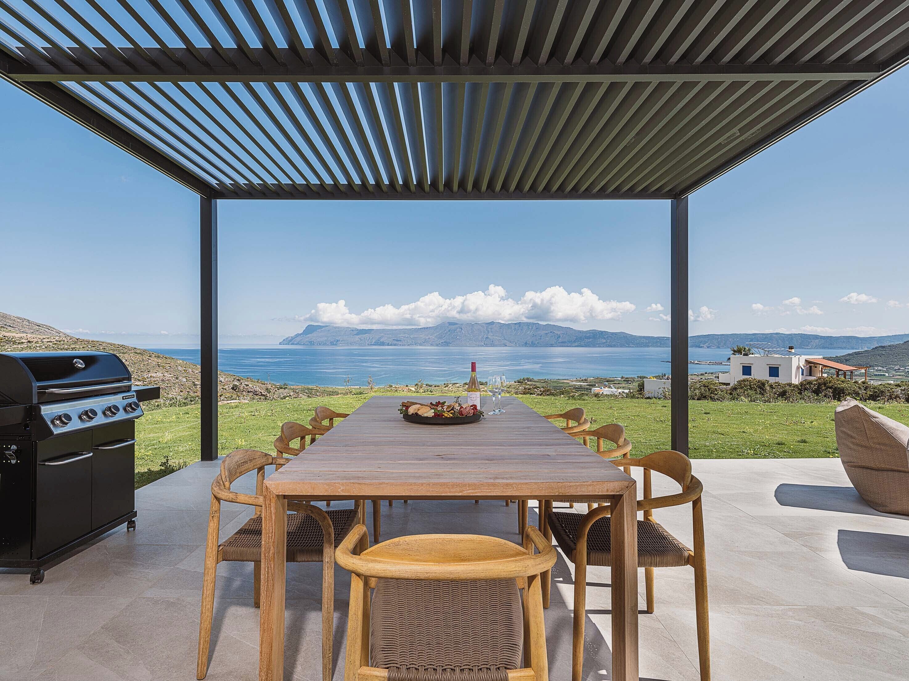 Un espace extérieur aménagé pour prendre les repas, avec vue sur la mer et les montagnes.