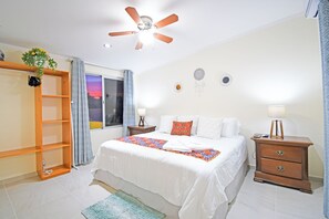 Relax in this inviting room featuring a large bed, a wardrobe, and a nightstand with a lamp.