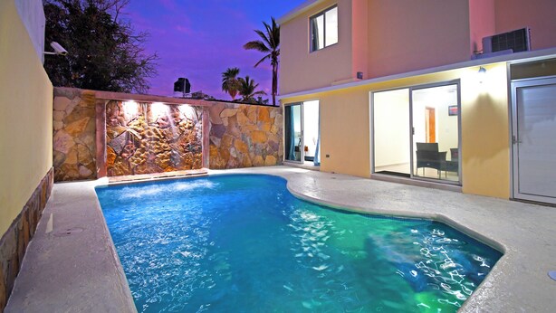 Una piscina con un muro de piedra y un edificio moderno al fondo.