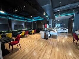Un restaurante moderno con suelo de madera, sillas rojas y amarillas, y una mesa de comedor central.