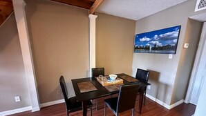 A dining area with a table set for four, a painting on the wall, and a wooden ceiling. - Cozy 1-bedroom condo with WiFi in Houston, TX (Houston)