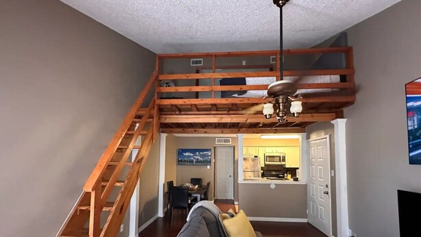 A loft-style living space with a wooden staircase, a dining area, and a kitchen. - Cozy 1-bedroom condo with WiFi in Houston, TX (Houston)