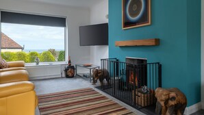 A cozy living room with a sofa, a fireplace, and a TV mounted on the wall. - Awel Fryn - Three Bedroom Cottage, Sleeps 6 (Hen Golwyn)