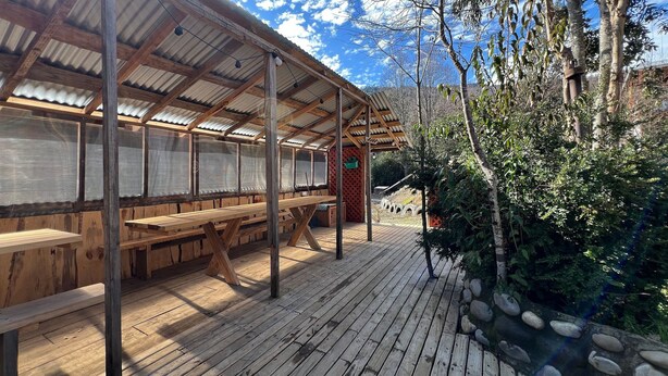 A covered outdoor seating area with wooden benches and a metal roof. - Oceana Suites Rayen Lican-Ray (Villarrica)