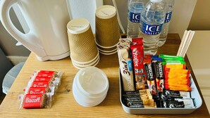 A breakfast setup with a coffee maker, paper cups, water bottles, and various food items. - Le Papillon Hotel Blackpool (Blackpool)