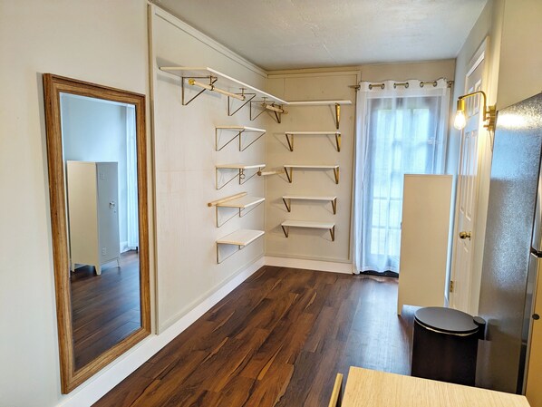 Una habitación con piso de madera, un espejo grande y estanterías empotradas.