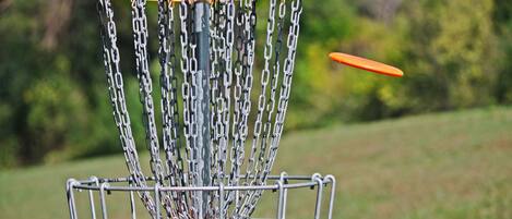A metal disc golf basket with chains and a yellow top.