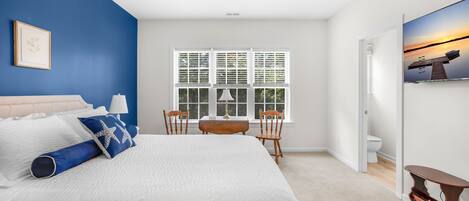 Upstairs primary bedroom with a blue accent wall, ceiling fan and TV.