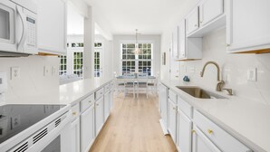 A modern kitchen with white cabinetry, a black countertop, and a wooden floor.