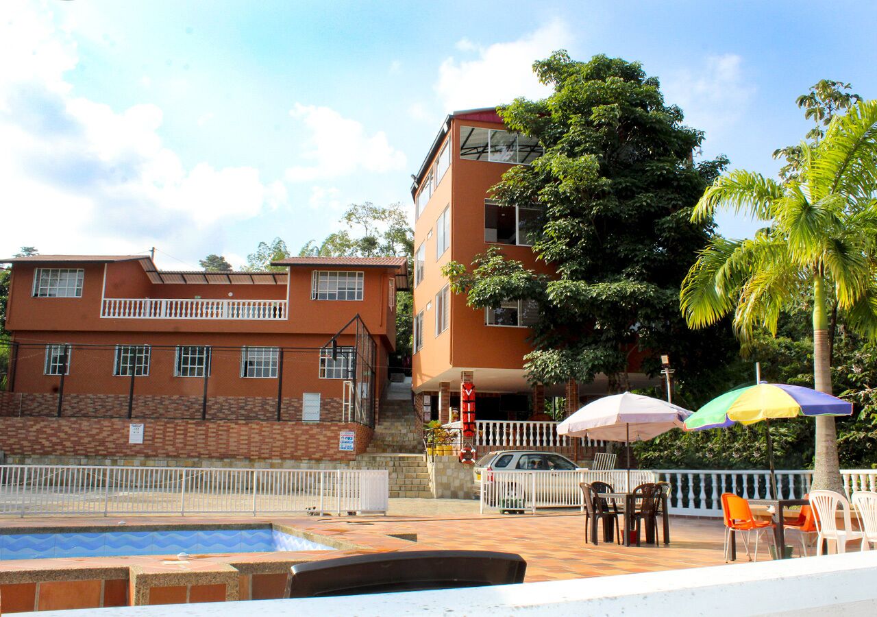 A hotel with a swimming pool, outdoor seating, and a staircase leading to the entrance.