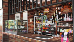 A brick-walled store with a glass display case, shelves stocked with snacks, and a QR code for payment. - Finca Hotel Villa Gladys (El Colegio)