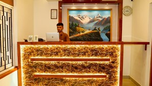 A reception desk with a laptop, framed certificate, and a painting of a mountainous landscape. - Thani Boutique Hotel (Kathmandu)