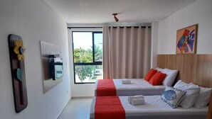 Una habitación de hotel con dos camas, un ventanal grande, un ventilador de techo y obras de arte en las paredes.