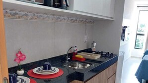 Una cocina compacta con un lavamanos, una cafetera y un pequeño banco.