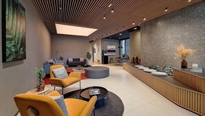 A modern reception area with a counter, seating, and a large painting. - Nik Perdizes (São Paulo)