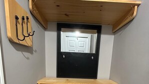 Kulmakaappi, jossa on ovi, pieni hylly ja seinään kiinnitetyt koukut.