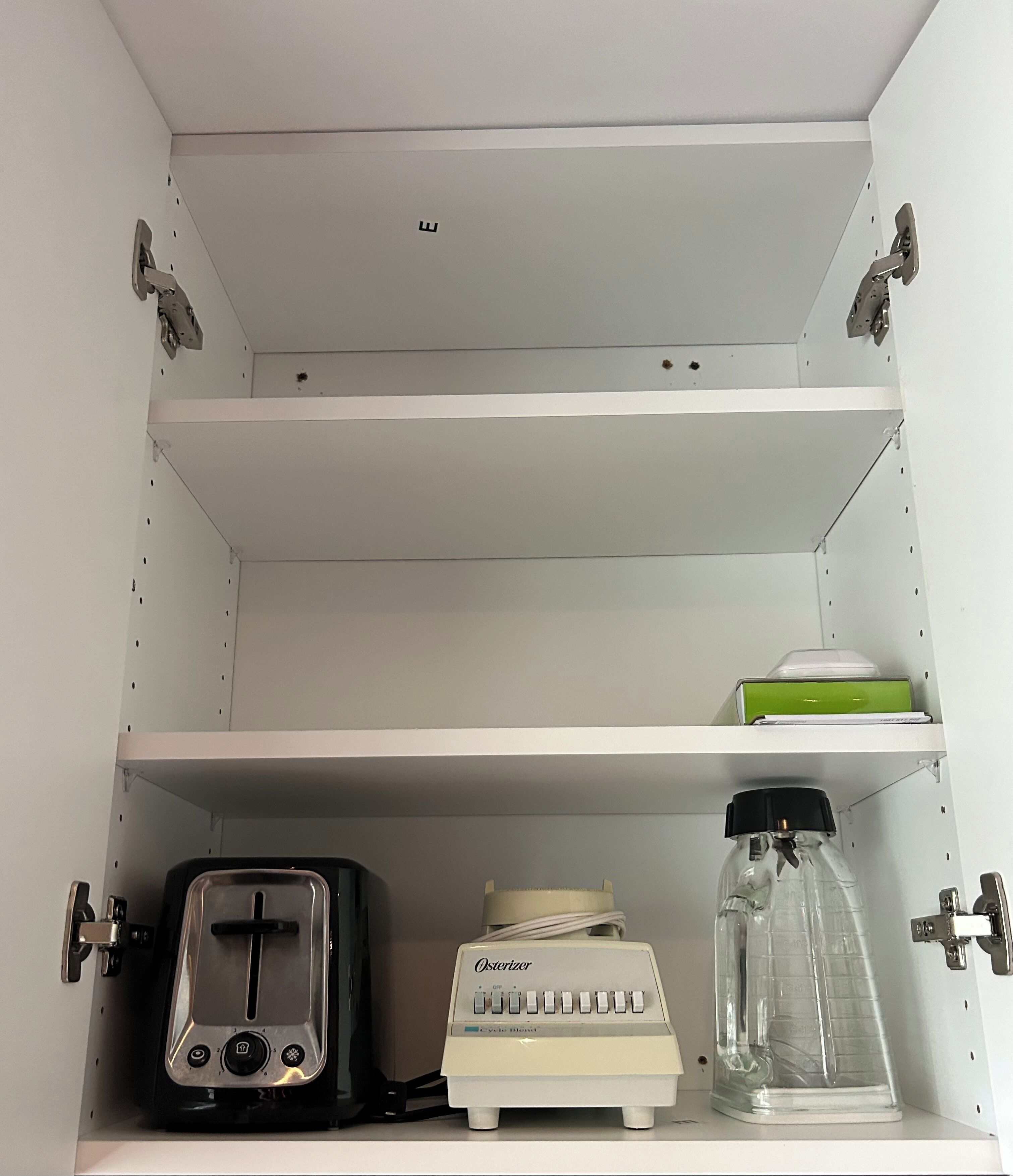 A white shelf unit with a toaster, a Osterizer juicer, and a clear plastic container.