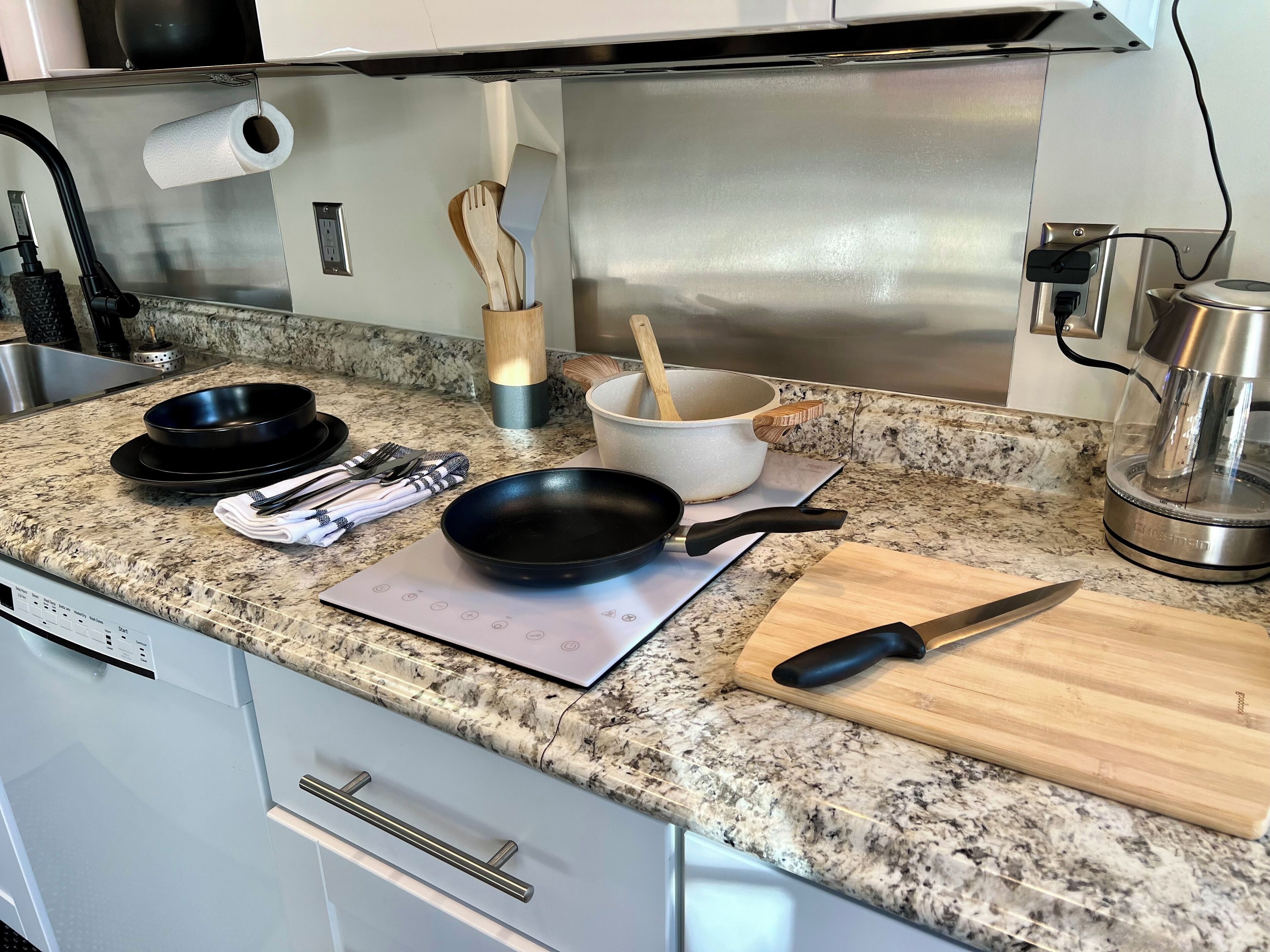 Une cuisine équipée de plans de travail en granit, d’une cuisinière, d’une machine à café et de divers ustensiles.