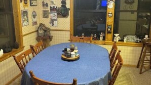 Ein Esszimmer mit einem runden Tisch, der mit einer blauen Tischdecke bedeckt ist, umgeben von Holzstühlen.