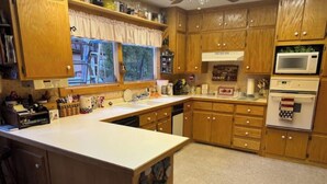 Eine Küche mit Holzausstattung, einer weißen Arbeitsplatte, einem eingebauten Backofen und einer Mikrowelle.