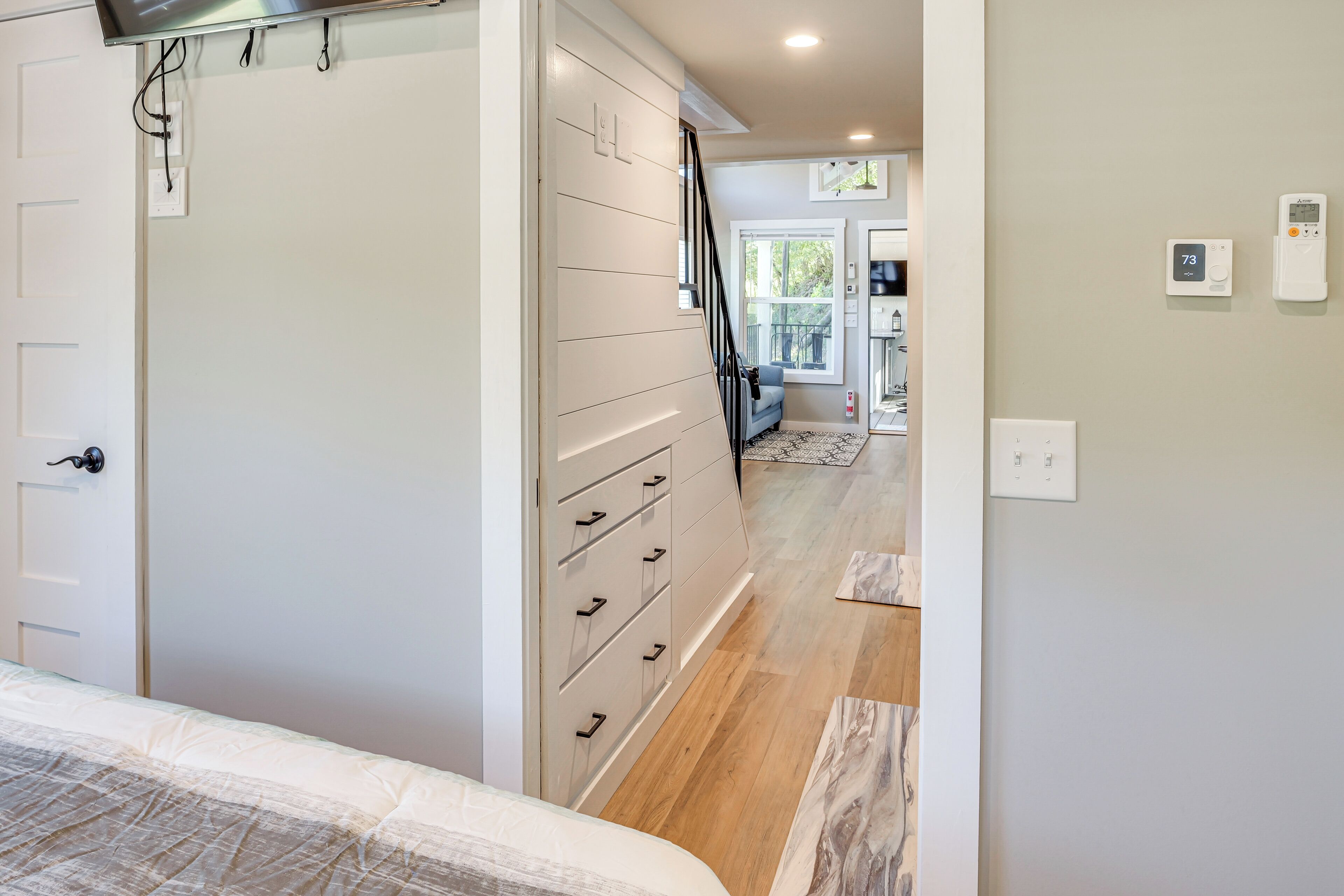 A bedroom with a bed, a dresser, and a staircase leading to another room.