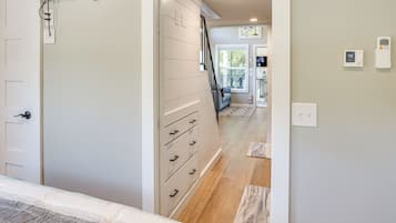 A bedroom with a bed, a dresser, and a staircase leading to another room.