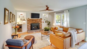 Un salón amplio con chimenea, sofá de cuero y ventilador de techo.