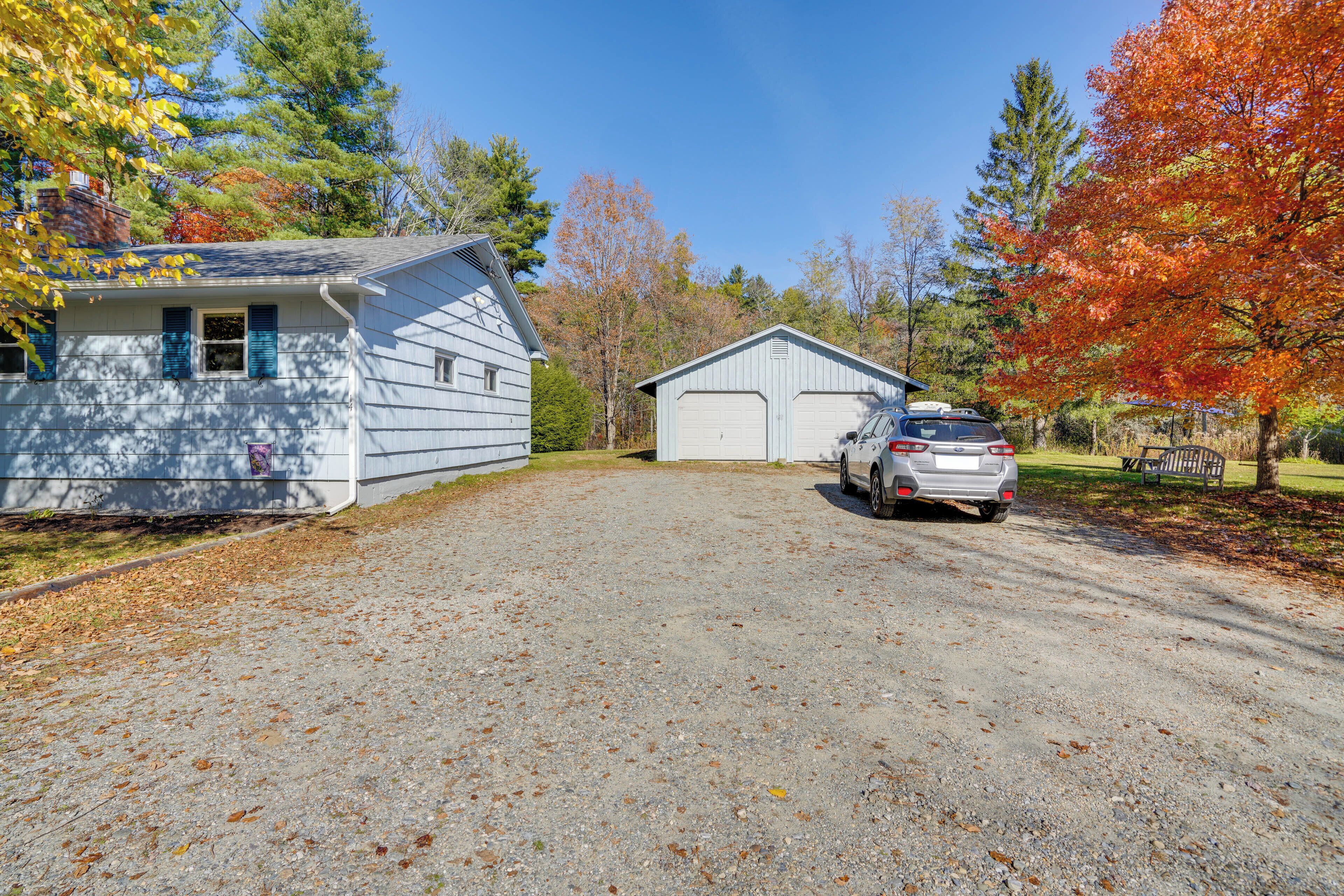 A gravel driveway leading to a garage with a car parked in front.