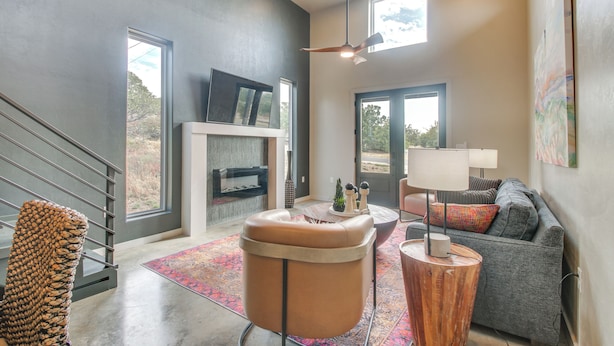 A modern living room with a fireplace, a sofa, a coffee table, and a staircase. - Modern Mtn-View Designer Home in Medicine Park (Medicine Park)