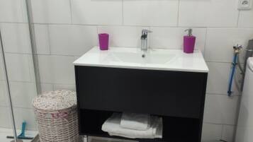 A bathroom with a white sink, two purple cups, a mirror, a wicker basket, a white towel, and a patterned rug.