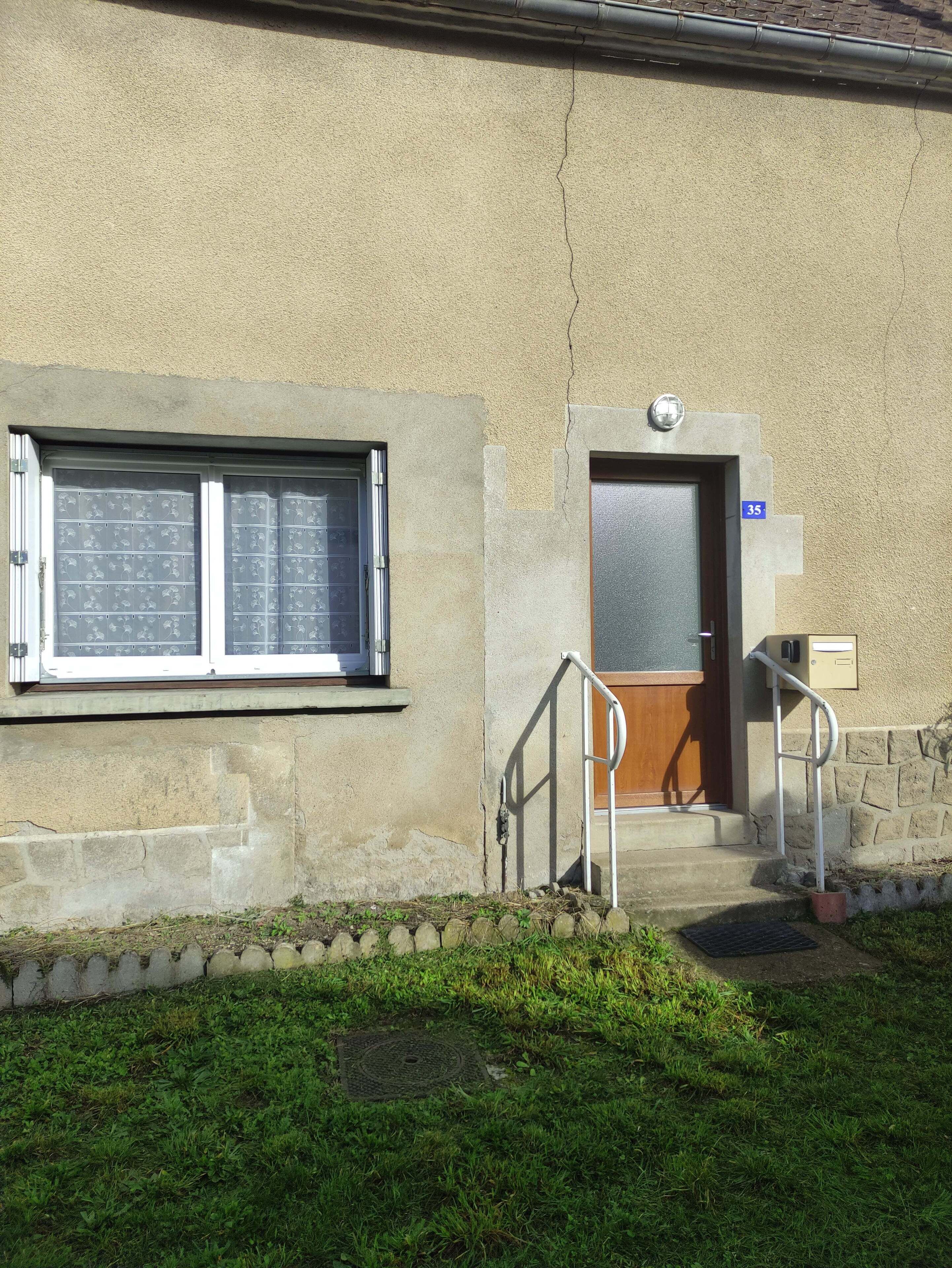 A building with a beige exterior, a wooden door, and a window with blinds.