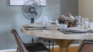 A round dining table with chairs, a fan, and a decorative centerpiece. - Large 1BR Retreat, Steps from Shops & Market (Pasadena)