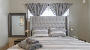 A neatly made bed with striped bedding, a tufted headboard, and two bedside lamps. - Large 1BR Retreat, Steps from Shops & Market (Pasadena)