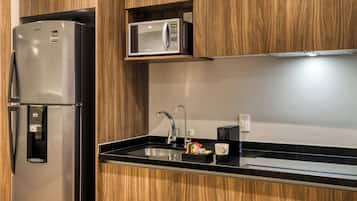 Una cocina moderna con un refrigerador de acero inoxidable, un microondas y un lavamanos empotrado.