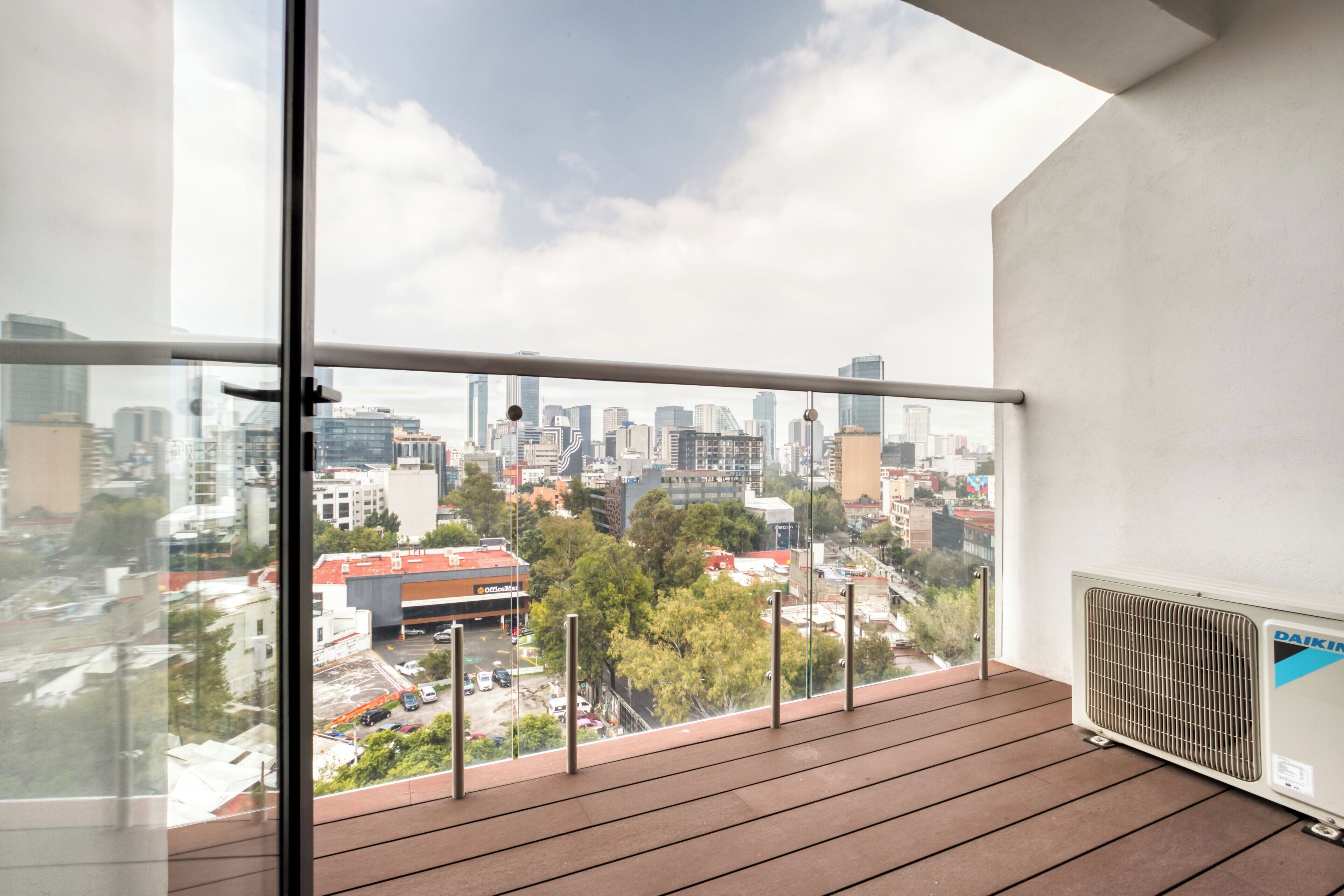 A balcony with a city view, a radiator, and a glass door.