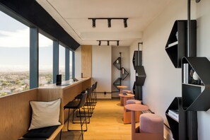 A modern interior with a long bench seating area, a bar counter, and a view of the city. - ULIV Mexico City (Mexico City)