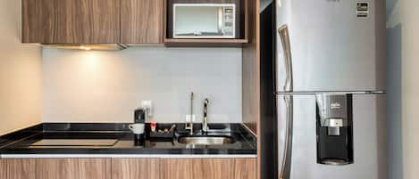 Una cocina moderna con armarios de madera, un refrigerador de acero inoxidable, un microondas integrado y un dispensador de agua.