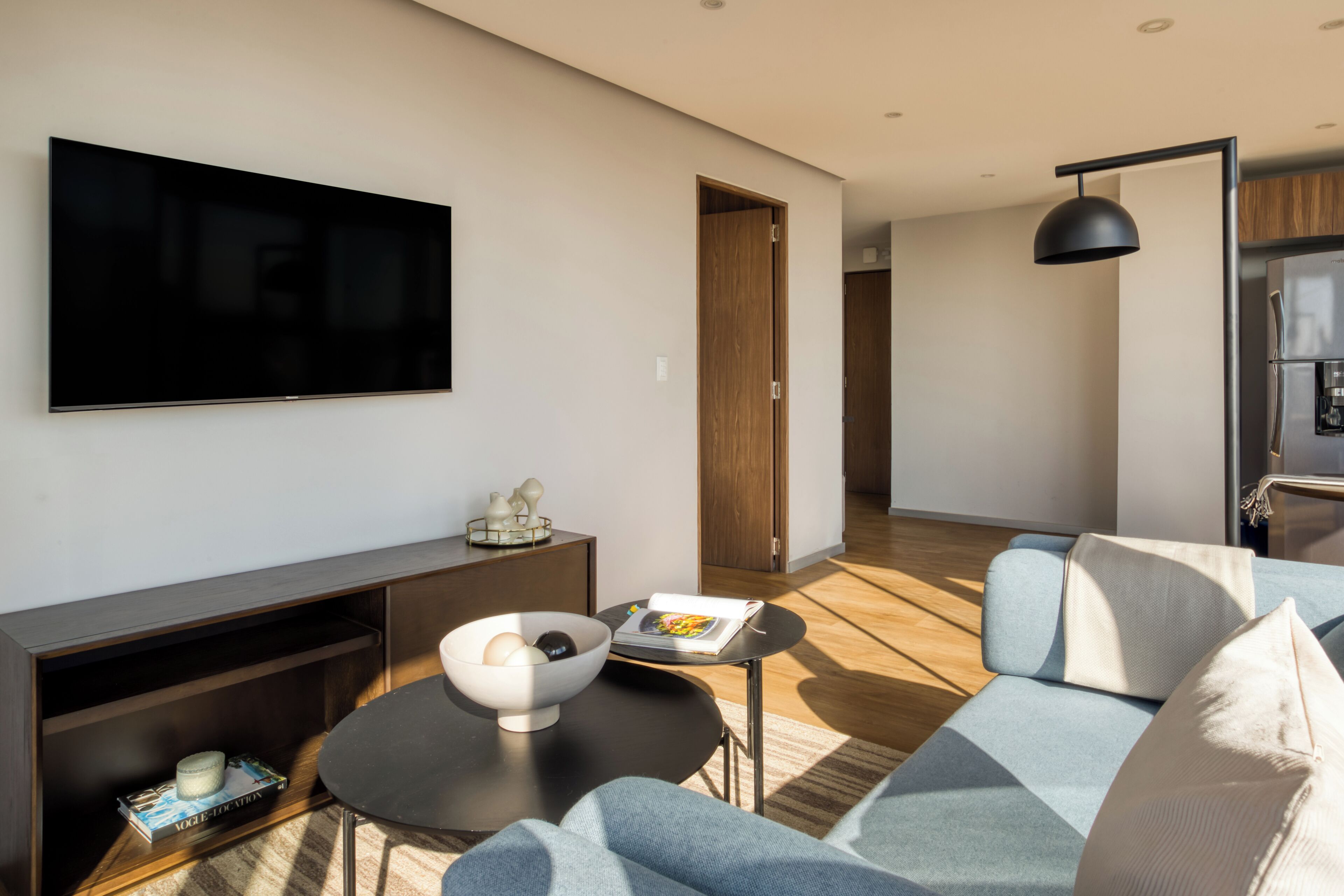 A modern living room with a flat-screen TV, a sofa, a coffee table, and a bookshelf.