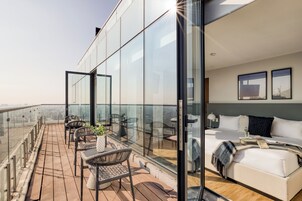 A modern hotel room with a balcony, a bed, and a view of the city.