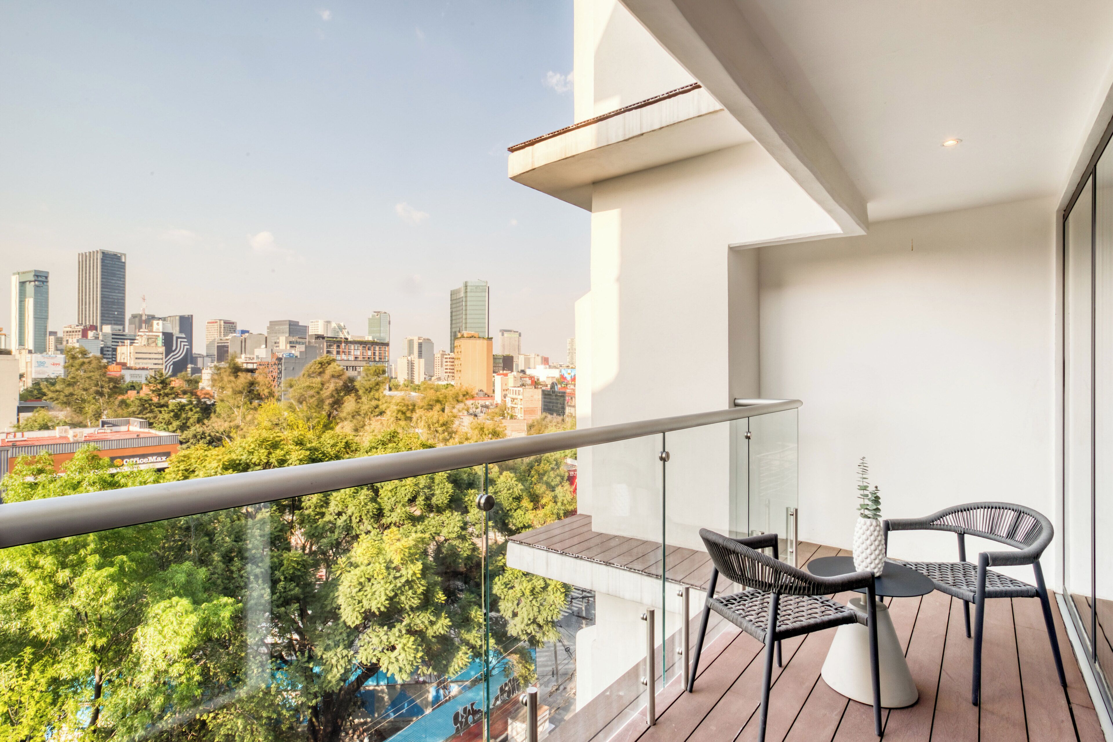 A balcony with a city view, a table, and two chairs.