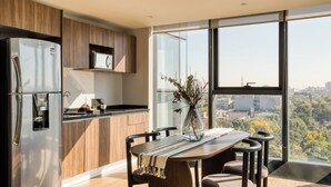 Een moderne keuken met een groot raam, een eettafel met stoelen en een koelkast.