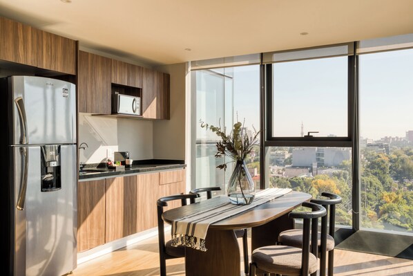 A modern kitchen with a large window, a dining table with chairs, and a refrigerator. - ULIV Mexico City (Mexico City)