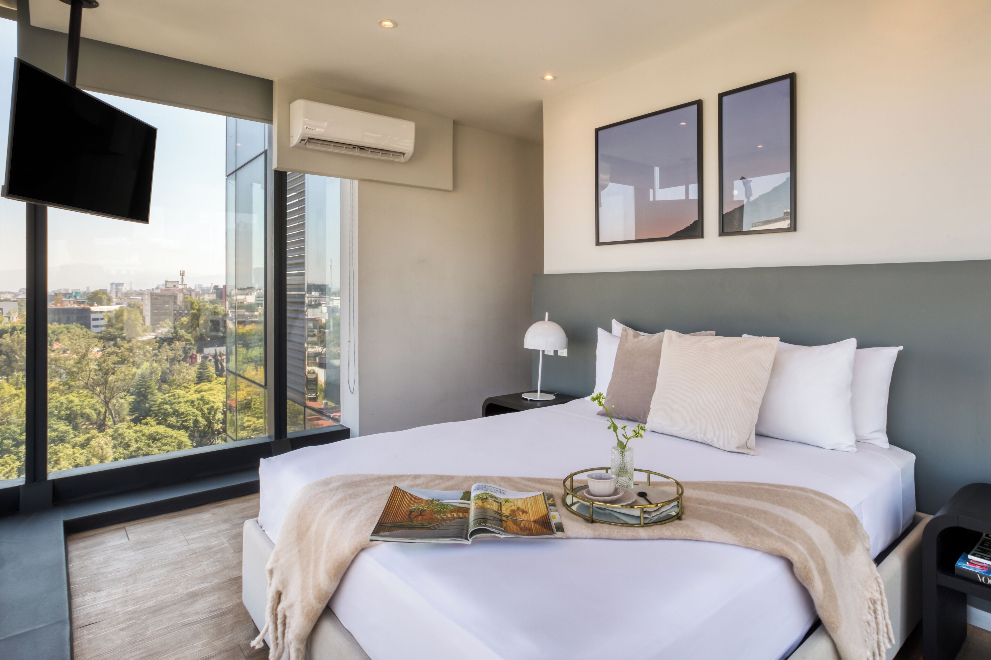 Ein modernes Hotelzimmer mit einem großen Bett, einem Fernseher und Blick auf die Stadt.