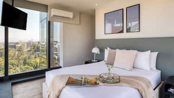 Una habitación de hotel moderna con una cama grande, televisión y vistas a la ciudad.