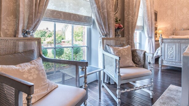 Une pièce comprenant deux fauteuils rembourrés, une table d’appoint en bois et une console blanche agrémentée d’un miroir.