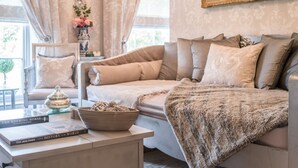 Un salon chaleureux avec un canapé, une table basse ornée de livres et d’un vase décoratif, un miroir et un tableau accroché au mur.