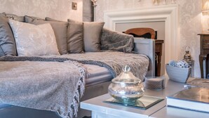 Une chambre à coucher avec un lit, une table de chevet, une lampe, un miroir et une cheminée.