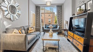A modern living room with a grey sofa, a coffee table, and a TV on a wooden cabinet. - No. 1 - Laurel Cottage - Pass the Keys (York)