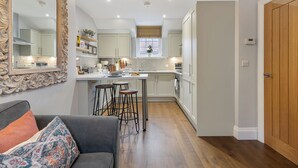 Una cucina moderna con mobili bianchi, un'isola centrale con sgabelli e un ampio specchio decorativo a parete.