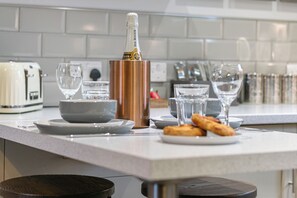 A kitchen counter with a champagne bottle, glasses, and pastries. - No. 3 - Lime Tree Cottage - Pass the Keys (Middlethorpe)